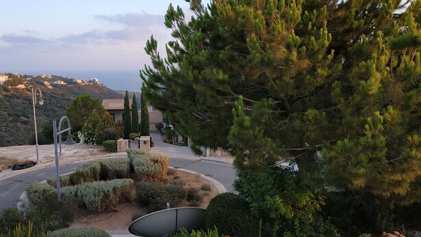 A residential area with a road, trees, and houses on a hillside. - Luxurious 3 bedroom villa with private pool garden and sea view (Kouklia)