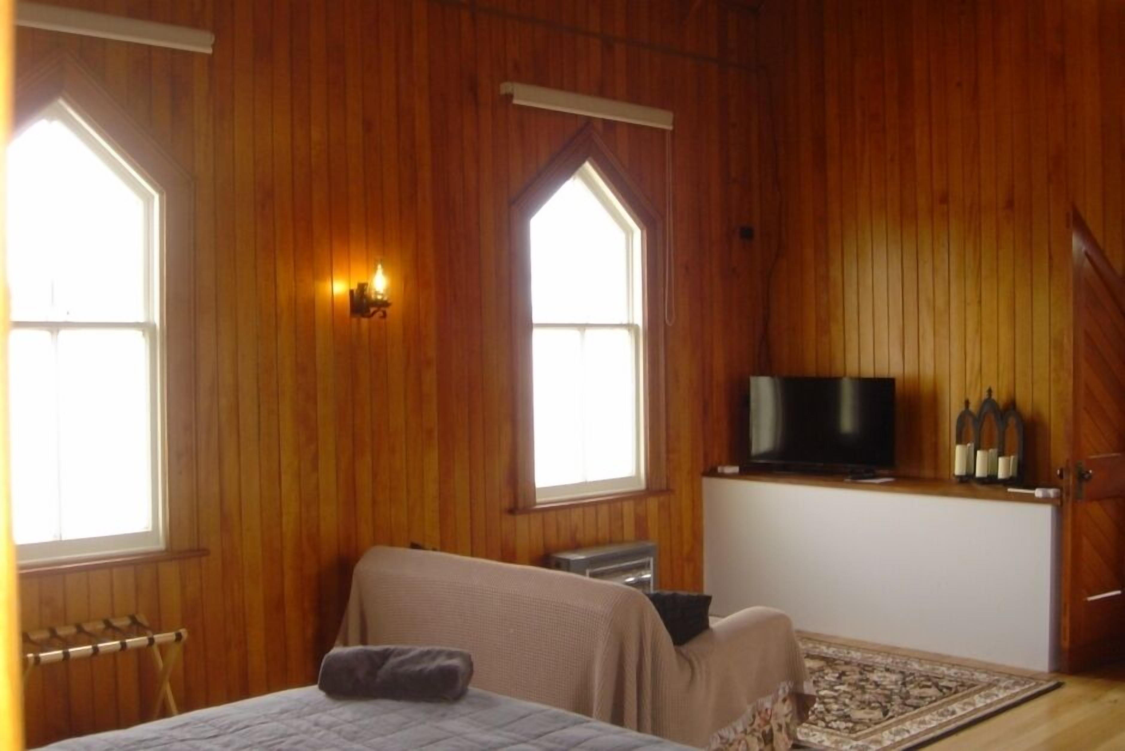 A room with wooden walls, a bed, a television, and a small table.