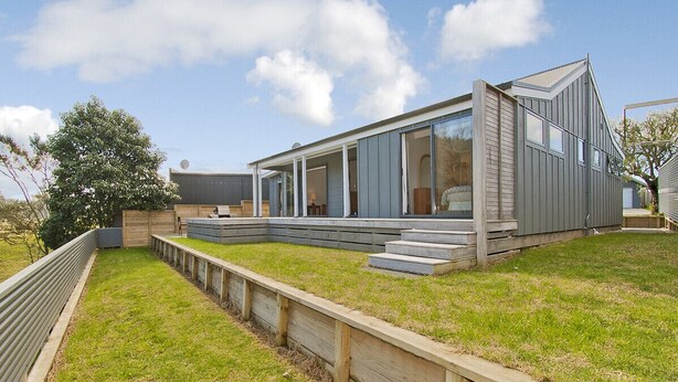 A modern house with a flat roof, large windows, and a wooden deck.