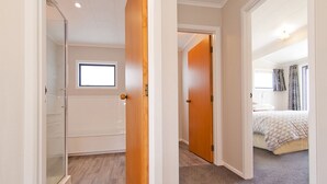 A bedroom with a bed, a window, and a door leading to another room.