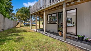 Ein modernes Haus mit Holzterrasse, großen Fenstern und einem gepflegten Rasen.