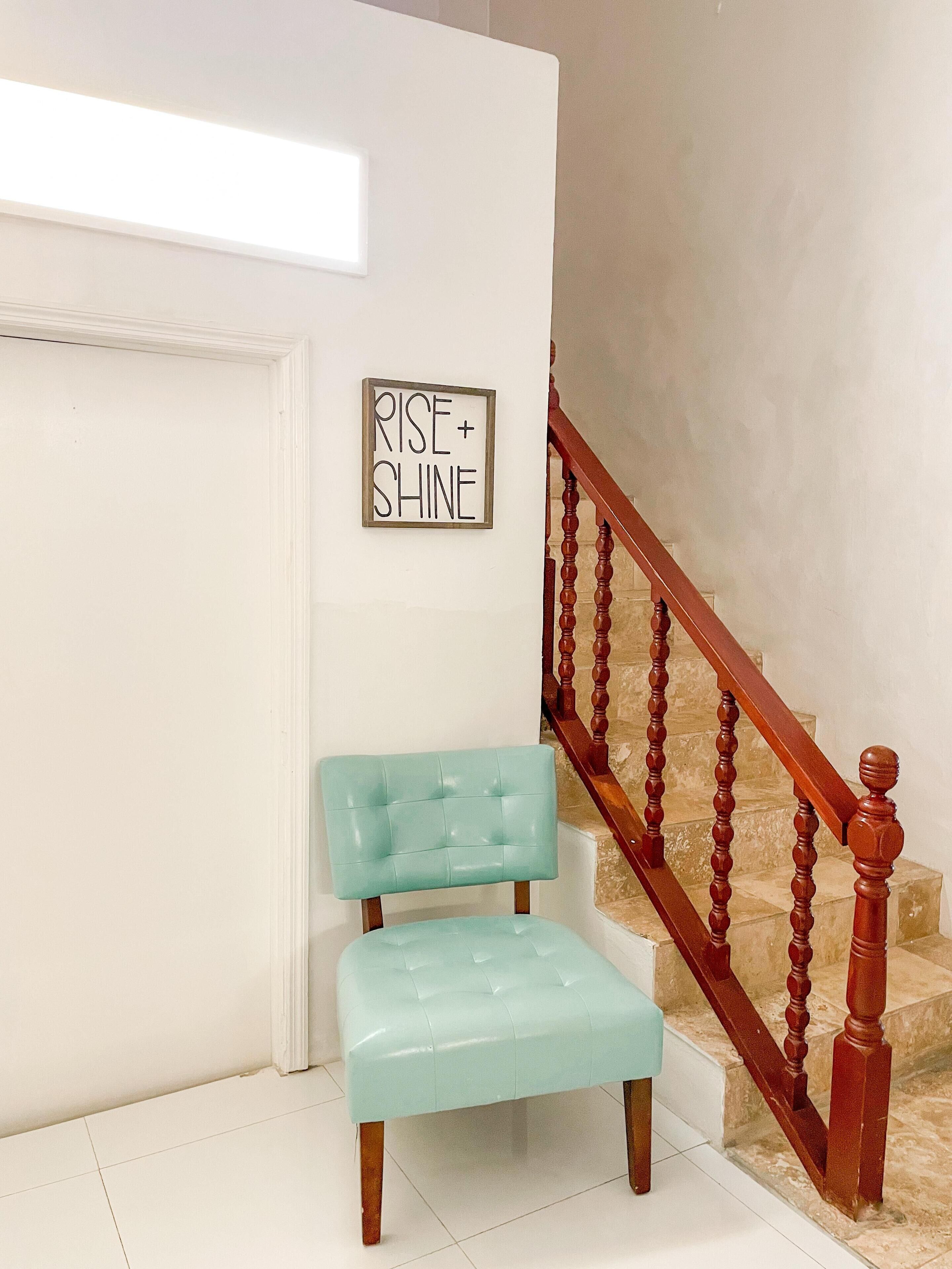 A staircase with wooden balusters and a light blue upholstered bench against a white wall.