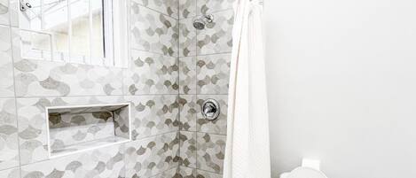 Une salle de bain avec une douche, des toilettes et une petite fenêtre.