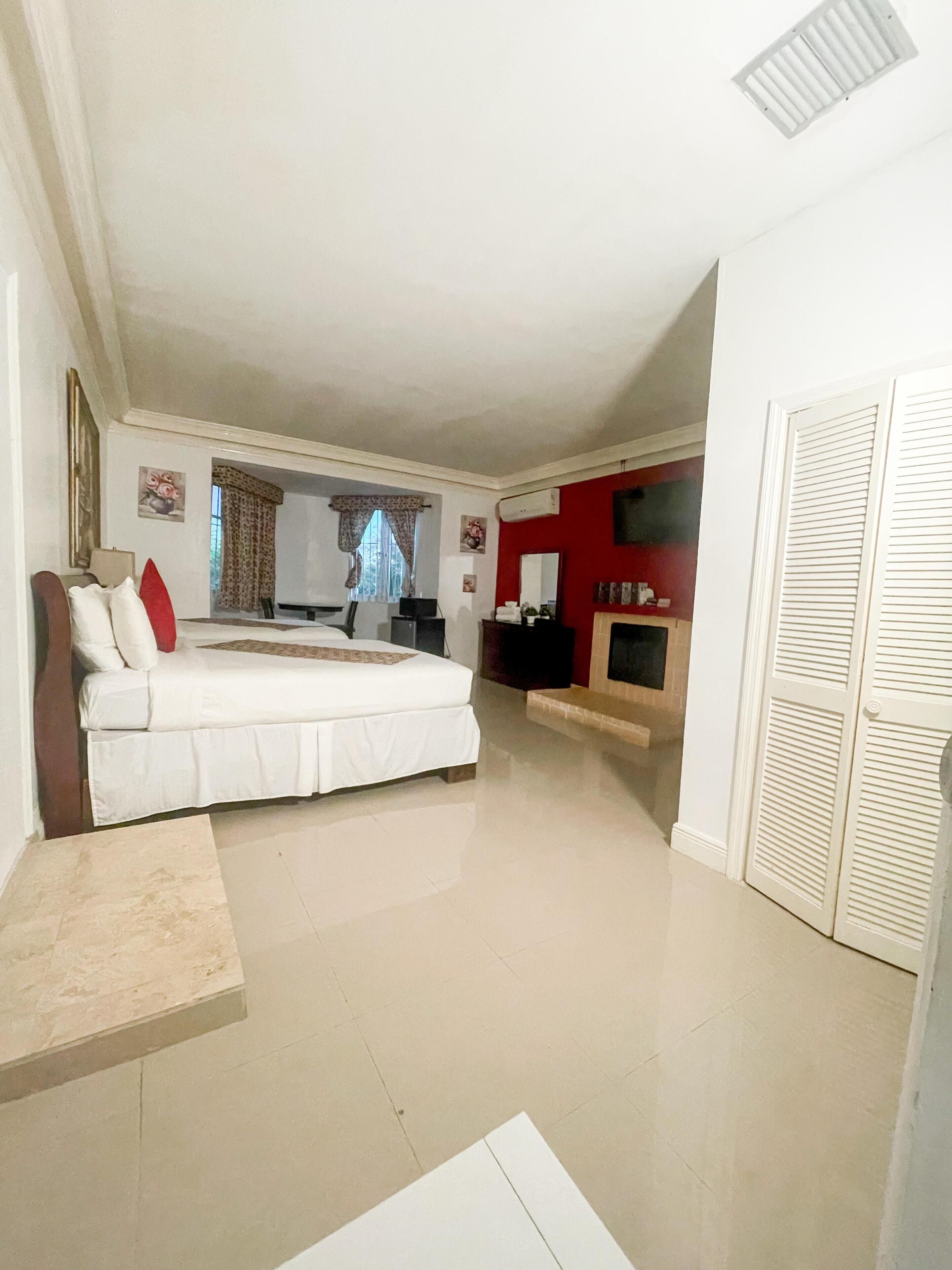 Un dormitorio amplio con una cama grande, televisión y una pared de acento roja.