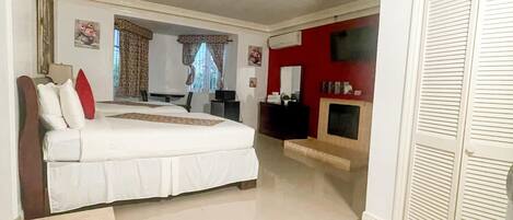 Un dormitorio amplio con una cama grande, televisión y una pared de acento roja.