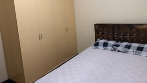Een slaapkamer met een bed, een houten hoofdbord en een beige garderobe.