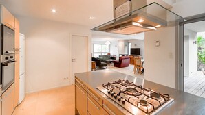 Una cocina moderna con una isla central, electrodomésticos de acero inoxidable y una campana extractora con cubierta de vidrio.