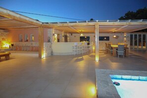 An outdoor patio area with a pool, seating, and a bar.