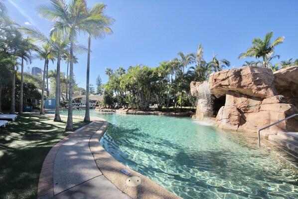 Relax by the pool surrounded by lush palm trees and a well-maintained lawn.