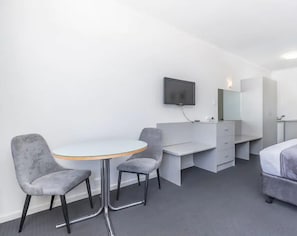 Relax in a stylish room with a round table, two chairs, a desk with a mirror, and a flat-screen TV.