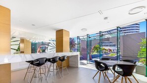 Une cuisine moderne dotée d’un plan de travail en marbre, de tabourets de bar noirs et d’une table à manger avec des chaises.