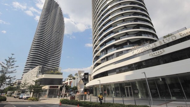 Deux immeubles modernes de grande hauteur, à l’architecture aux lignes courbes, dont l’un porte une enseigne indiquant « Oracle Blvd » et « Peppers ».
