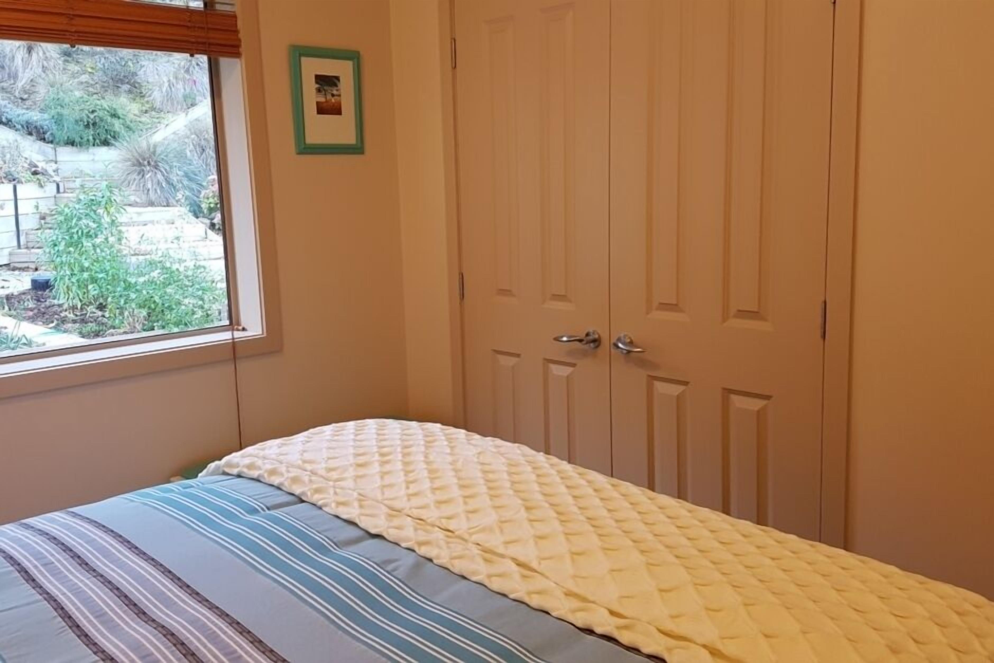A bedroom with a bed, a window, and a set of closed doors.