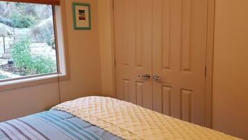 A bedroom with a bed, a window, and a set of closed doors.