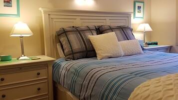 A neatly made bed with striped bedding, two bedside tables with lamps, and a dresser with drawers.