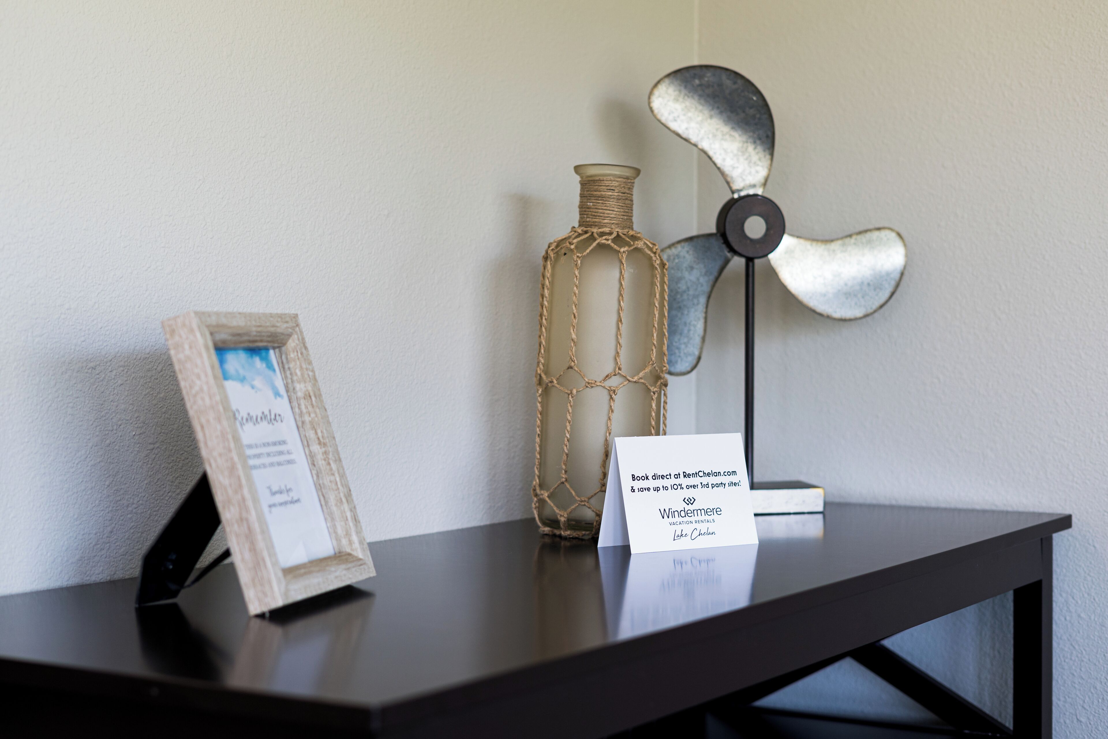 A table with a framed picture, a decorative bottle, and a fan.