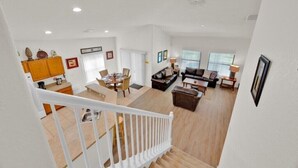 A spacious living area with a staircase, a dining area, and a kitchen. - More 4 your Money w/ Private South Facing Pool (Kissimmee)