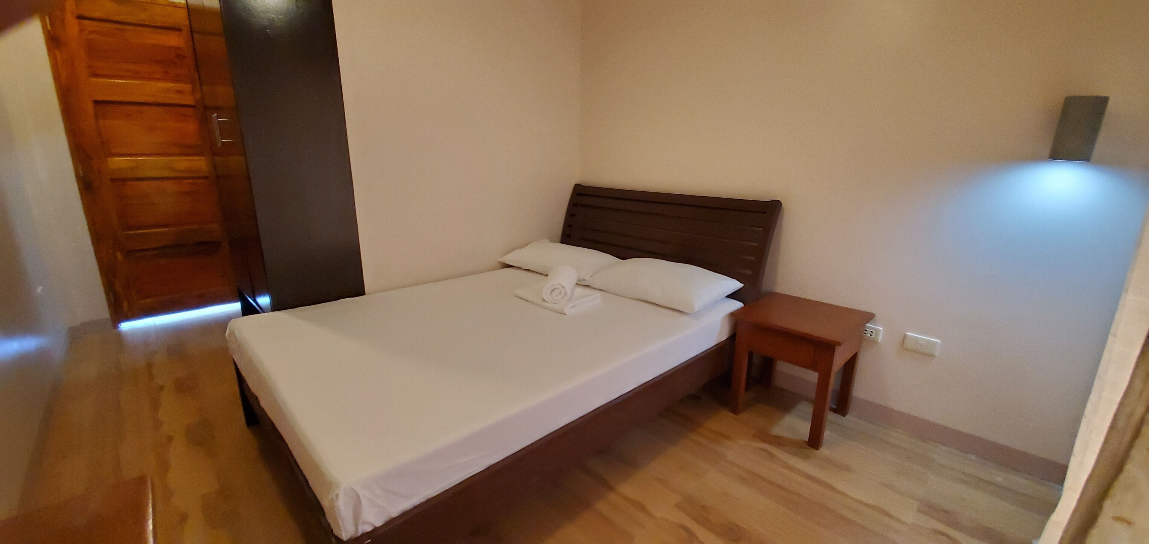 Ein Schlafzimmer mit einem hölzernen Bett, einem Nachttisch und einem Beistelltisch.