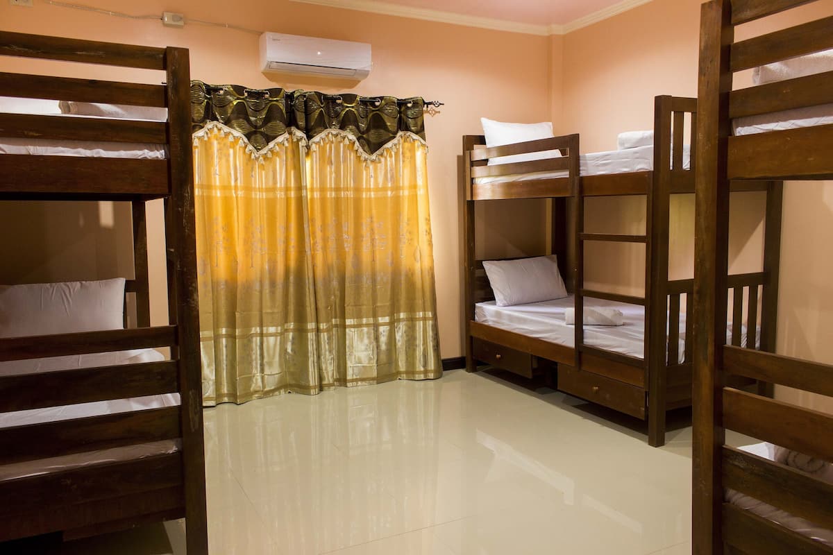 Une chambre avec des lits superposés, un rideau et un appareil de climatisation.