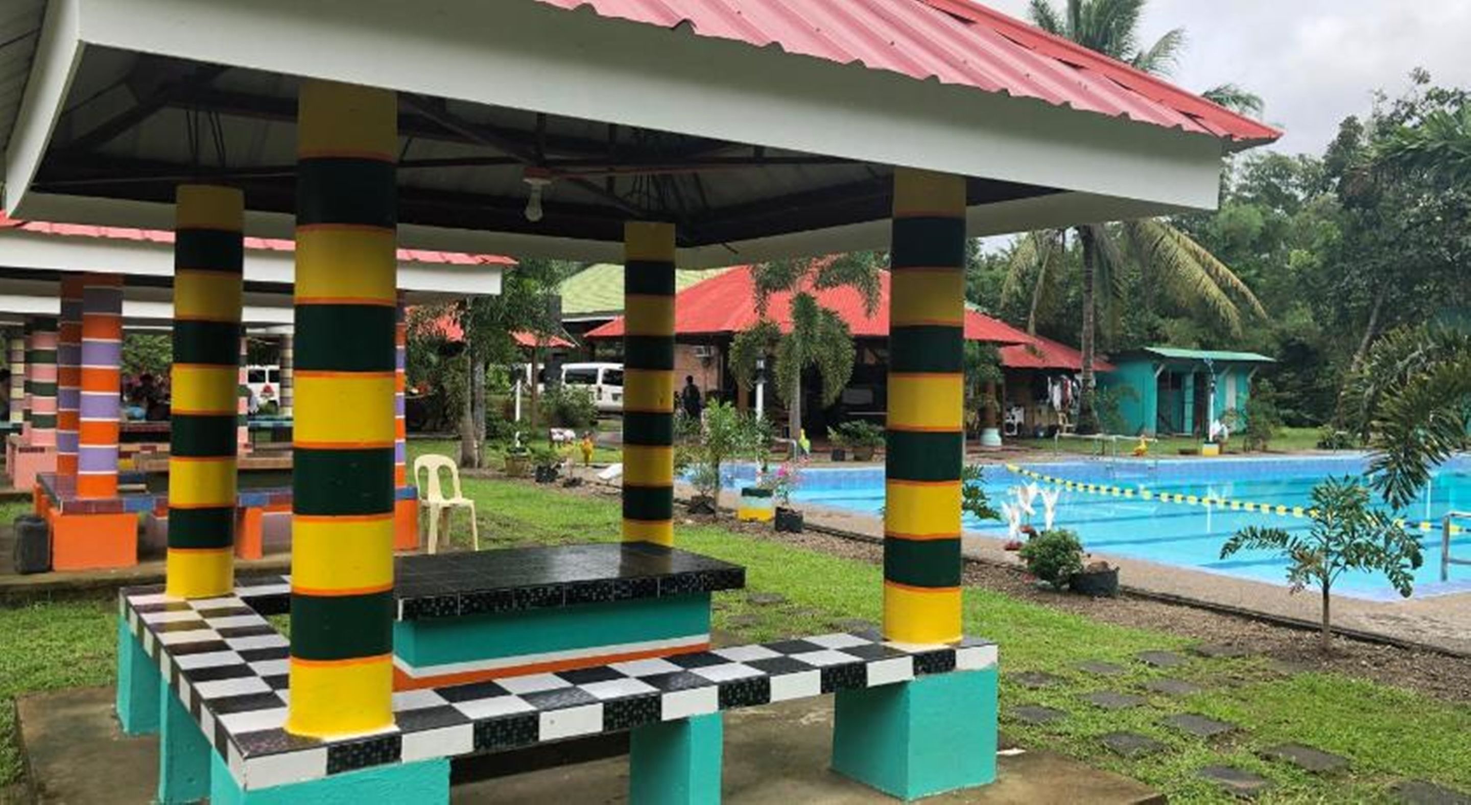 A covered outdoor area with a pool, colorful pillars, and a checkered bench.