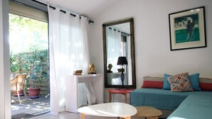 Ein Wohnzimmer mit einer Couch, einem Tisch, einem Spiegel und einer Zimmerpflanze.
