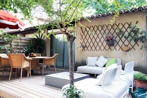 Un patio con mobili in vimini, un divano bianco e un piccolo albero.