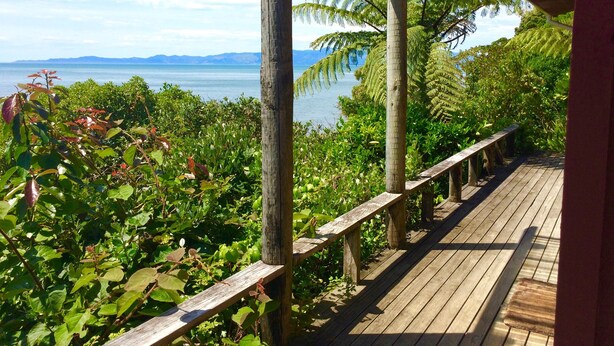 Una terraza de madera con vistas a un cuerpo de agua y montañas distantes.