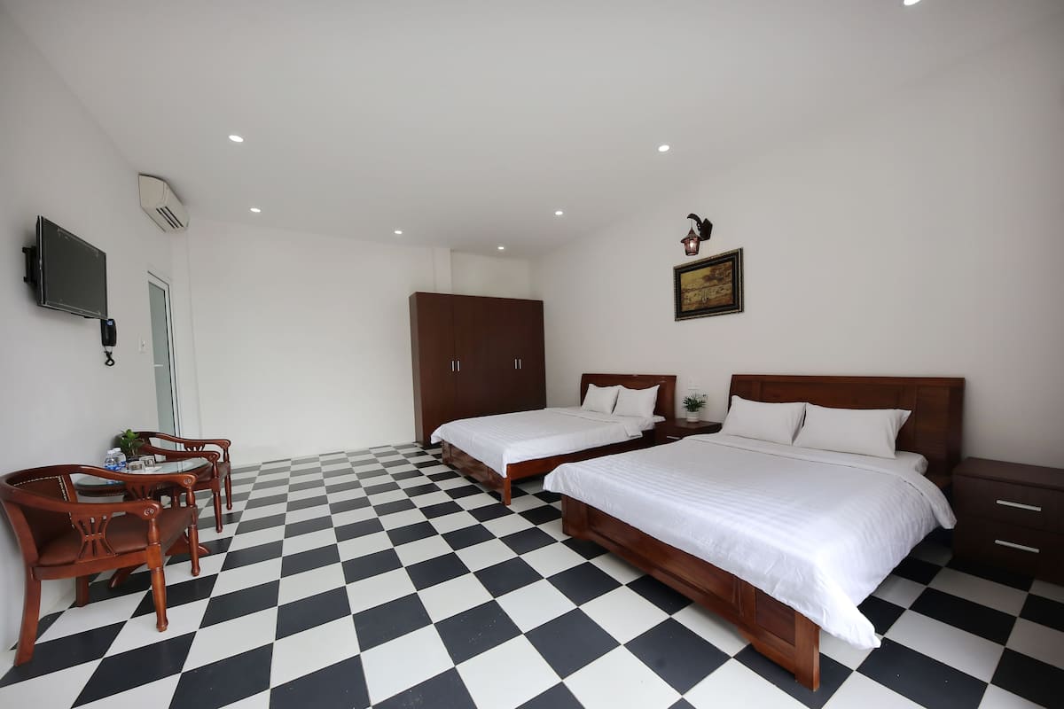 Une chambre d’hôtel avec deux lits, une armoire en bois, un bureau avec une chaise et un téléviseur.