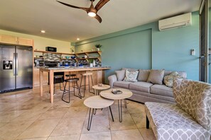 A modern kitchen with a central island, bar stools, and a dining table. - Condo w/ Lanai at Beginning of Road to Hana! (Paia)