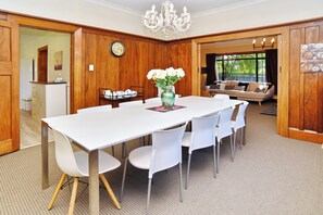 A dining area with a white table and chairs, a vase with flowers, and a clock on the wall.