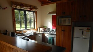 A kitchen with wooden cabinets, a microwave, a stove, and a sink.