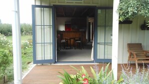 An open wooden door leading to a room with a kitchen area, a dining table, and chairs.