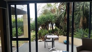 A room with a sliding glass door leading to an outdoor patio area with a table, chairs, and potted plants.