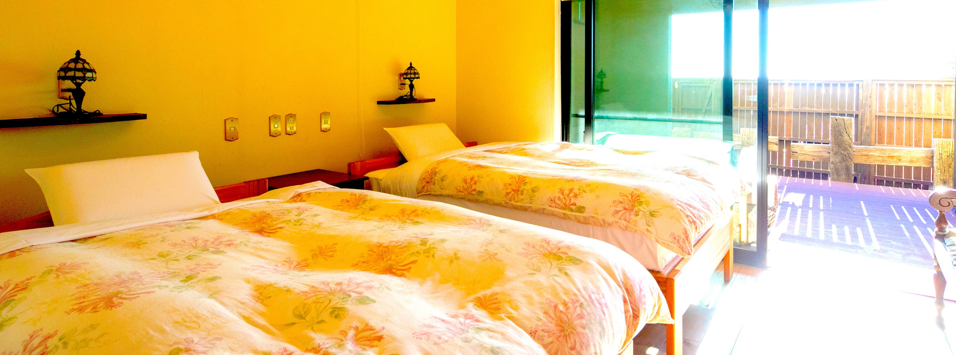 Een kamer met twee bedden, een raam met uitzicht en een deur naar een buitenruimte.