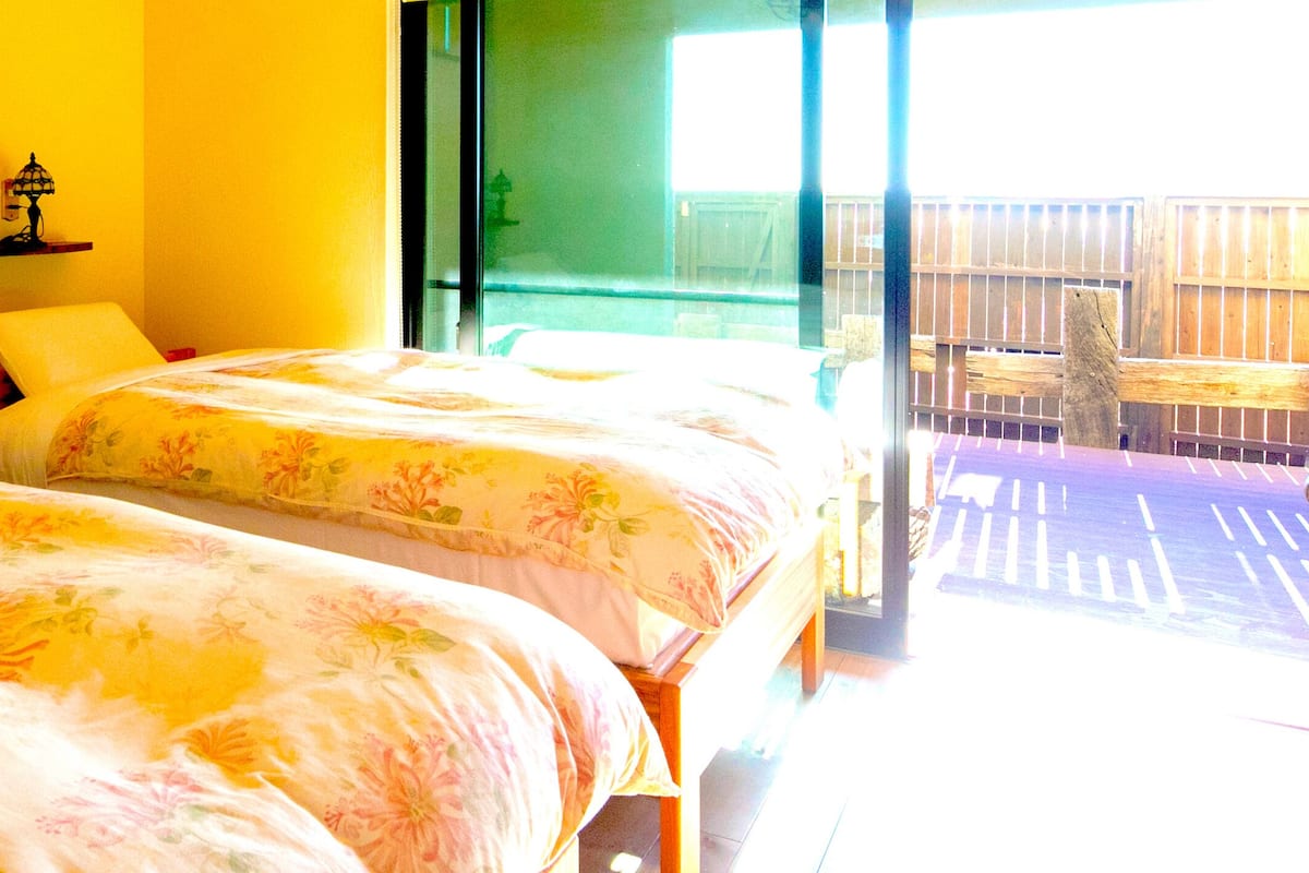 A room with two beds, a window with a view, and a door leading to an outdoor area.