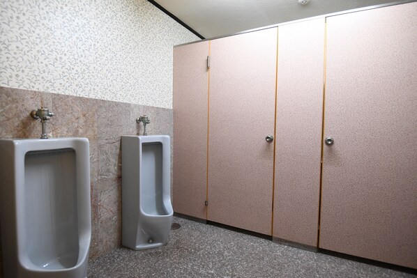 A men's restroom with two urinals, a marble wall, and a tiled floor. - Toemu Nozawa (Nozawaonsen)