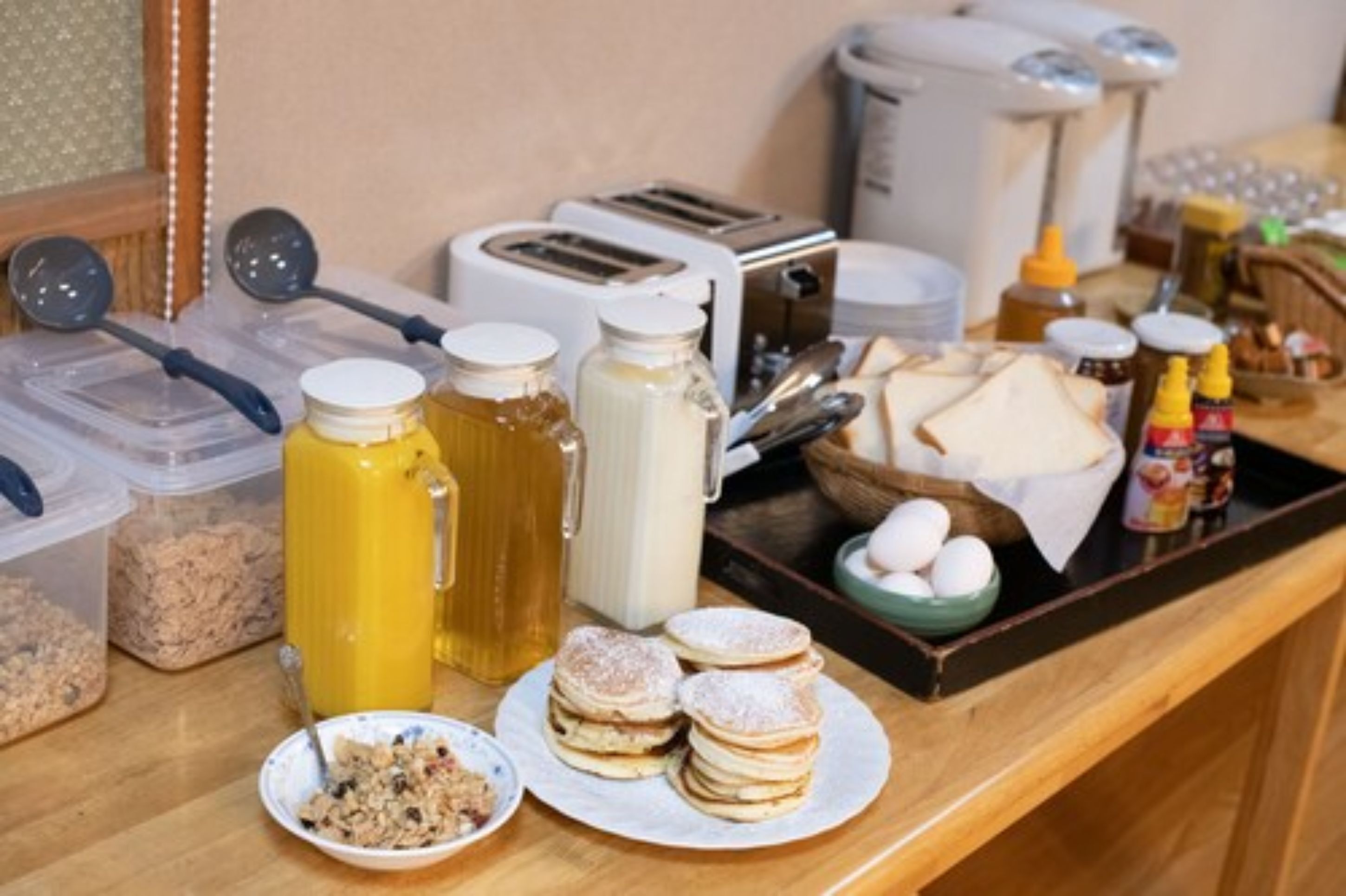 A breakfast buffet setup with various food items, condiments, and kitchen appliances.