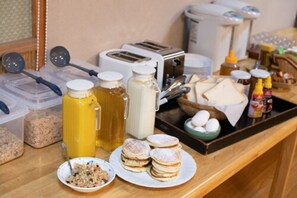 A breakfast buffet setup with various food items, condiments, and kitchen appliances.