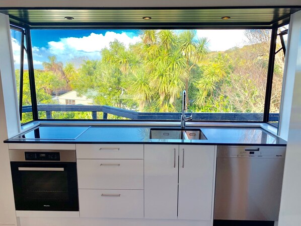 A kitchen with a large window, a sink, and a dishwasher.