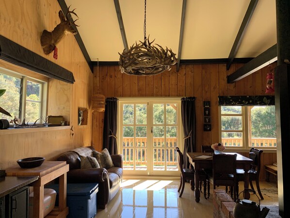 A wooden interior with a sofa, dining table, and chandelier.
