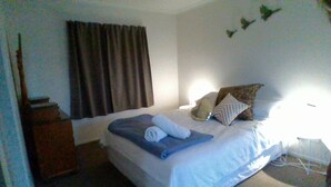 Une chambre d’hôtel avec un lit, une table de chevet, une lampe et une fenêtre avec des rideaux.