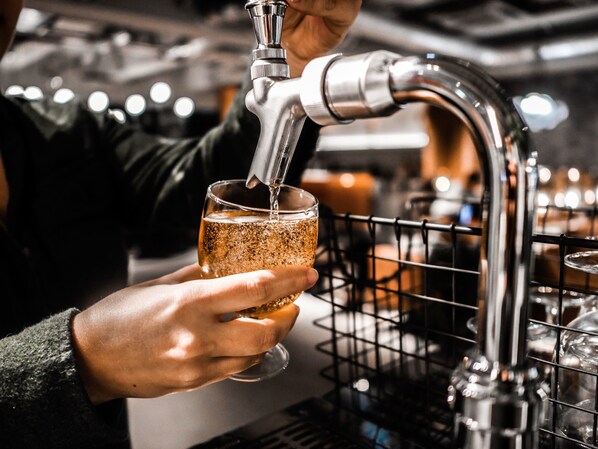 A person pouring a drink from a tap into a glass. - slash kawasaki (Kawasaki)