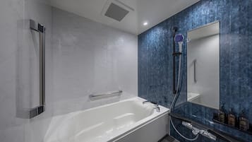 Un baño moderno con una bañera independiente, un cabezal de ducha de mano y un espejo grande.