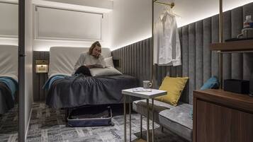 A hotel room with a bed, bedside table, and a small seating area.