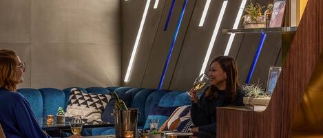 Un interior moderno con un sofá, una mesa con bebidas y una zona de bar.