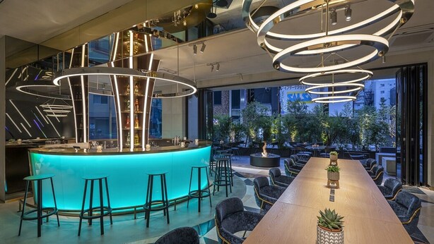 Zona de bar moderna con barra iluminada con neón y asientos.