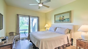 Une chambre à coucher avec un lit, un ventilateur de plafond, un tableau, un bureau et une chaise.