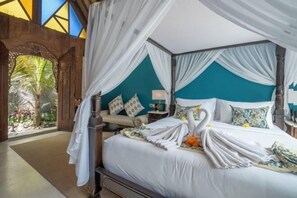Un lit à baldaquin avec des rideaux blancs, un mur d’accent de couleur turquoise et une vue sur la verdure à travers une fenêtre en arc de cercle.