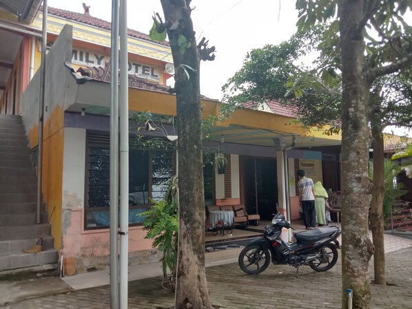 A hotel with a covered entrance, a staircase leading to the entrance, and a parked motorcycle.