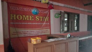 A reception desk with a 'HOME STAY' sign, a telephone, and a small box on the counter. - OYO 898 Joglo Family Hotel & Homestay (Mungkid)